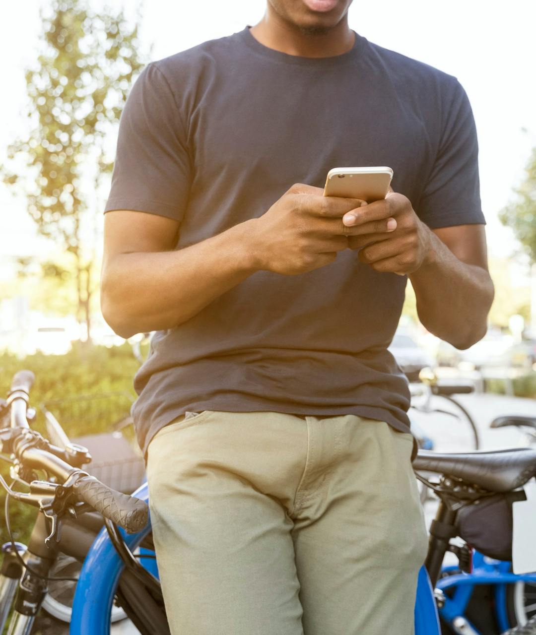 Person on their phone leaning against a bike